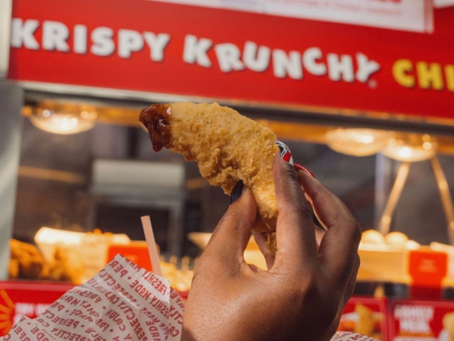 holding up a chicken tender with barbeque sauce on it