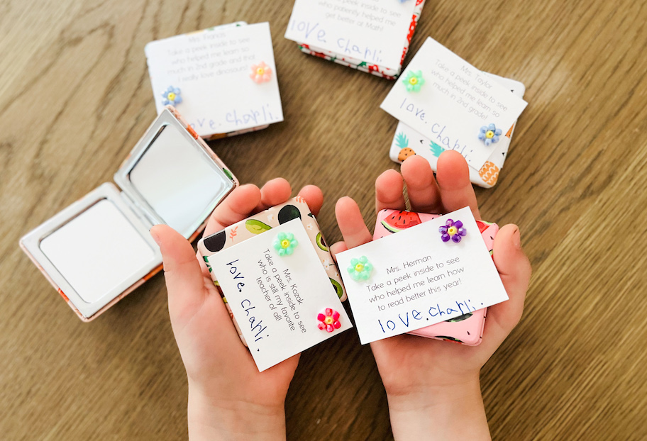 childs hands holding notes for teacher gift ideas with fruit themed compact mirrors