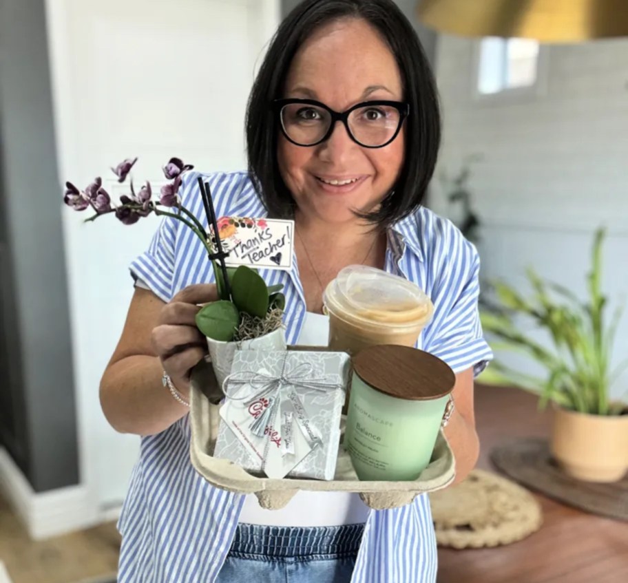 woman holding cup holder with candle plant and gift card for teacher