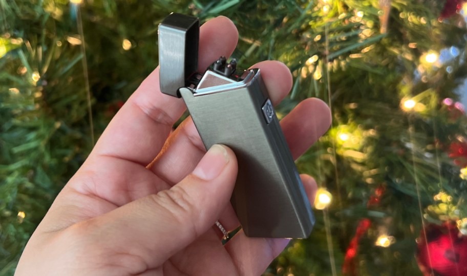 hand holding a rechargable lighter in front of christmas tree