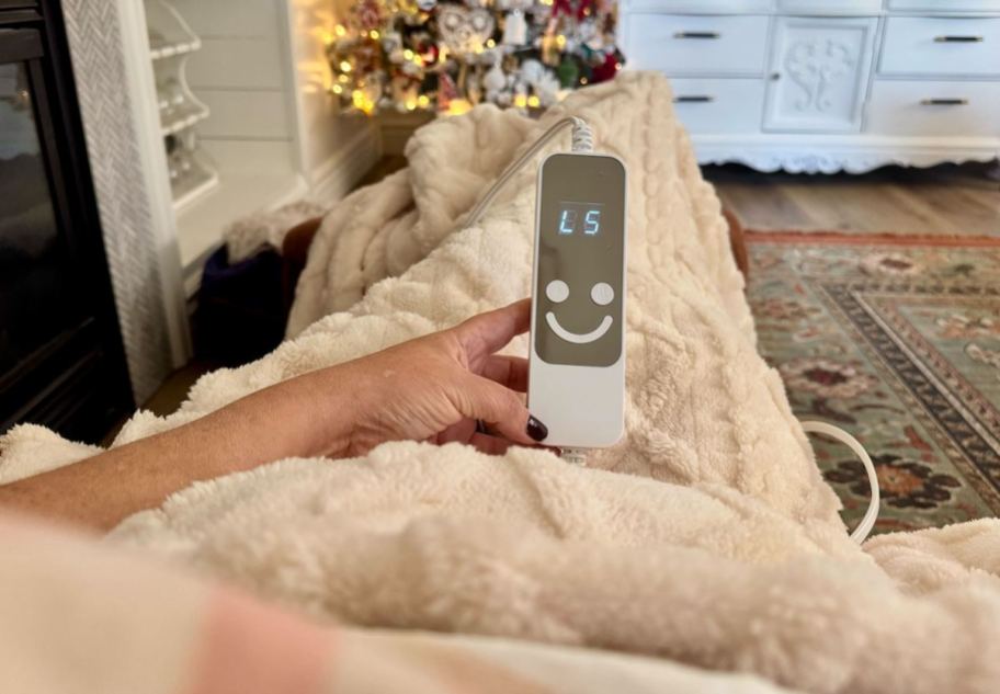 hand holding smiley remote to faux fur heated throw