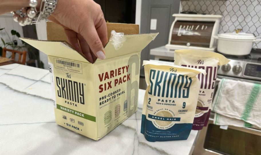 hand holding skinny pasta box on kitchen counter with bags of skinny pasta 