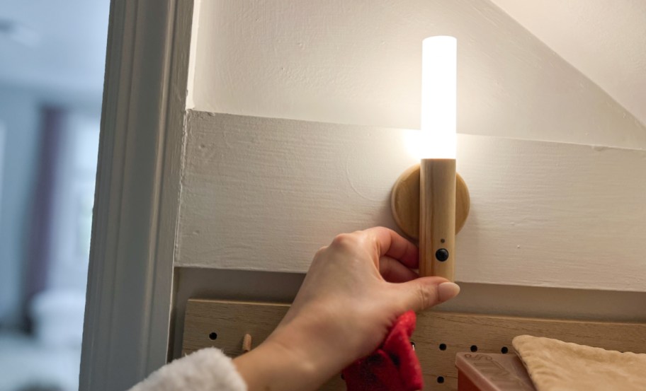 hand holding a wooden light on wall