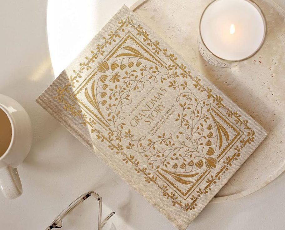 beige grandmas story book journal on countertop with candle and glasses