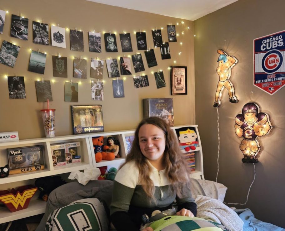 girl sitting on bed with photo clip lights and art photos on wall