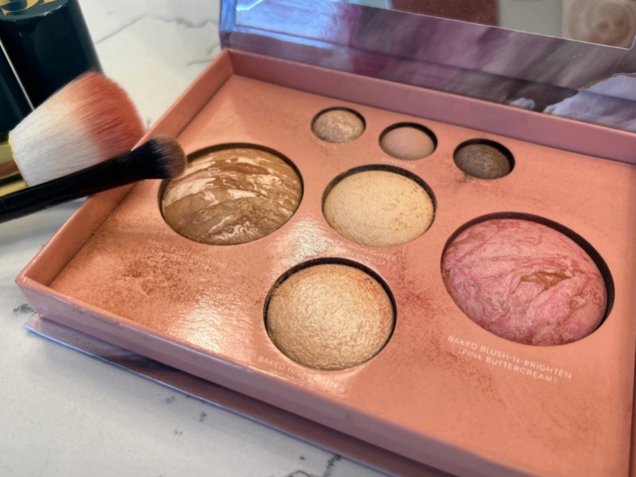 display of Laura Geller The Best of the Best Baked Face Palette with brushes next to it