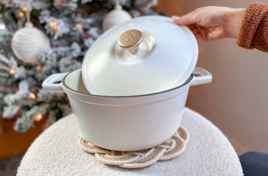 hand holding lid to white cast iron dutch oven