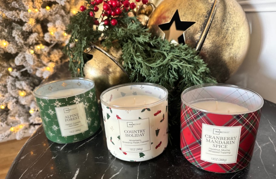 three mainstays candles from walmart lined up in front of christmas decor