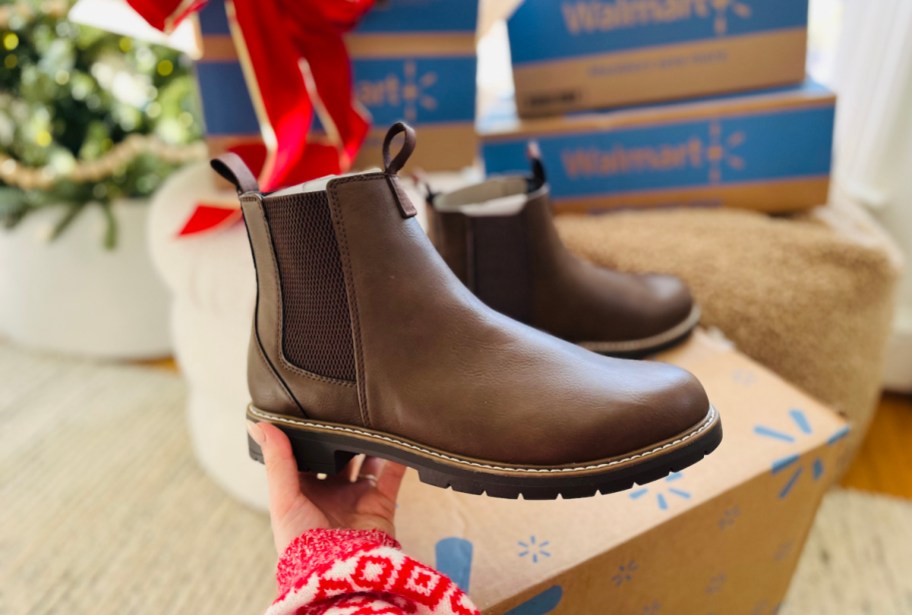 hand holding brown boot in front of walmart holiday boxes