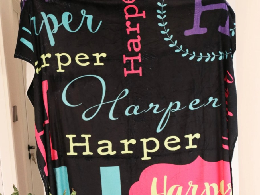 a black throw blanket with the name Harper in various colors and fonts