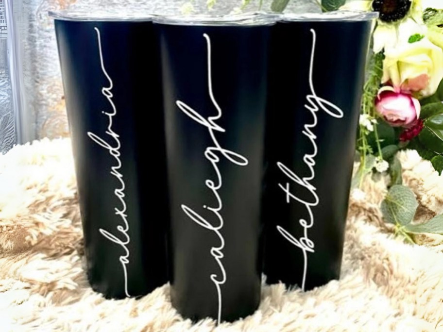 3 black tumblers with names on them in a white cursive font