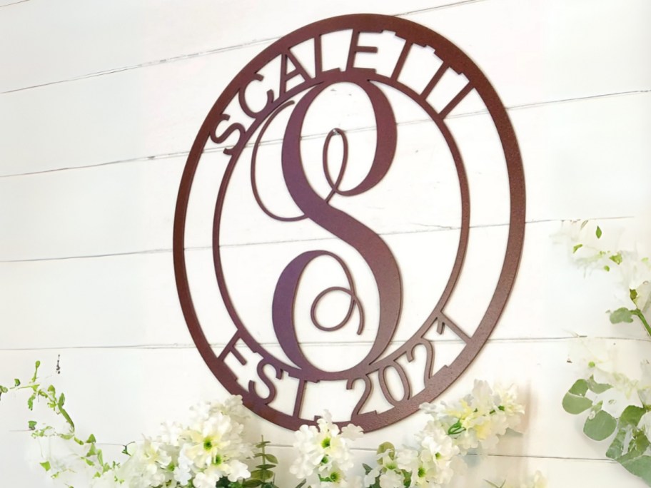 a brown color metal scroll round wall sign with a monogram and the family name and established date on a walll