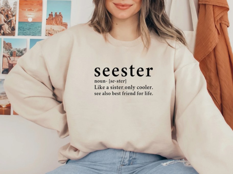 a woman wearing a cream sweatshirt that says "Seester"