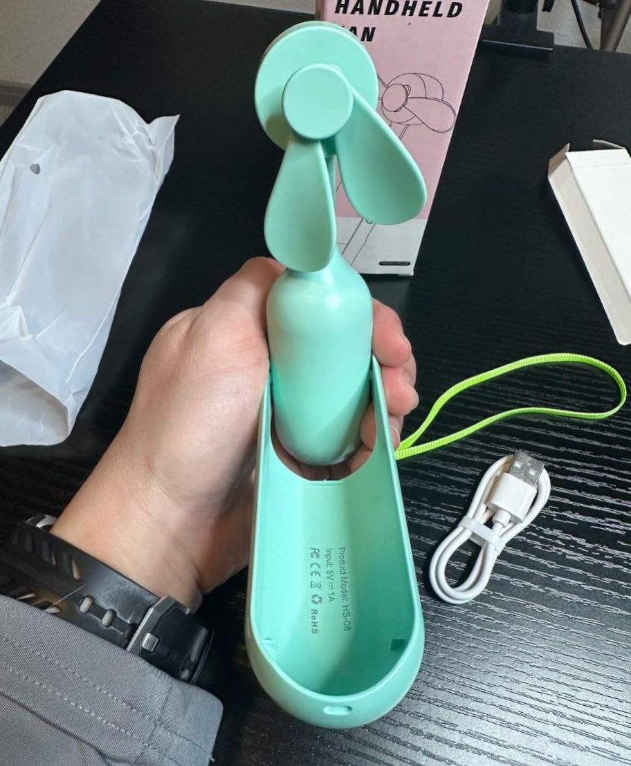 hand holding mint green portable handheld fan