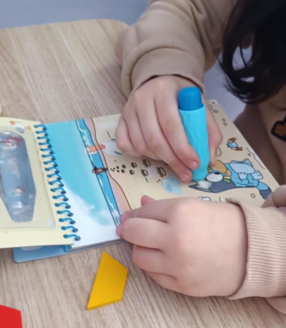 Close-up of child coloring an aqua art book