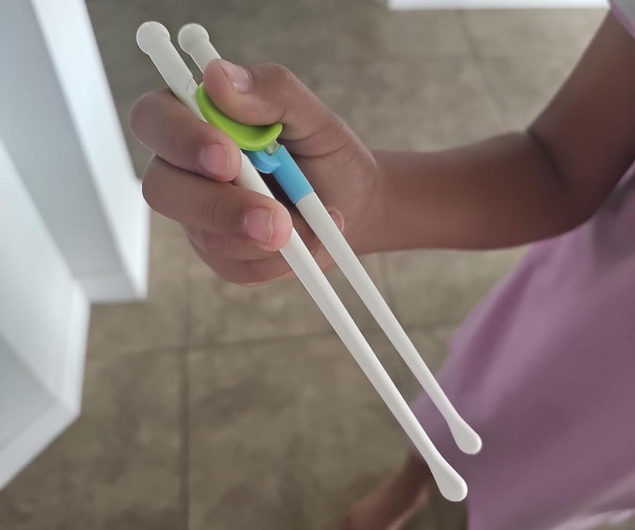 Childs hand holding chopsticks