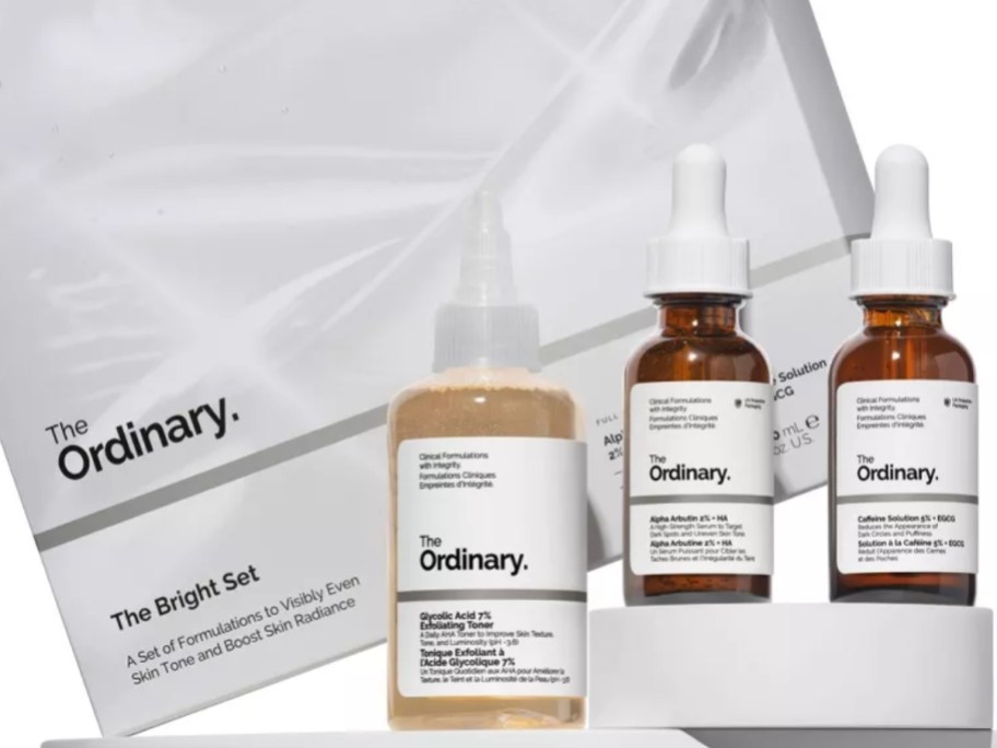 3 small bottles of The Ordinary skincare items next to a gift box they come in