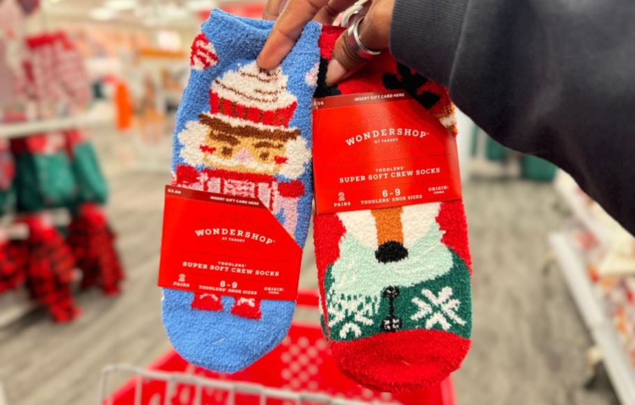 a womans hand holding 2 sets of wondershop holiday sock 3-packs with gift card holder