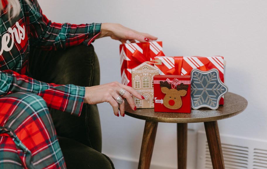 woman next to christmas gifts and amazon packaged gift cards