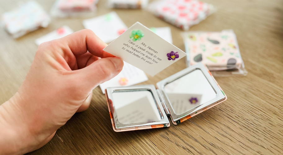 hand holding a card over small compact mirror