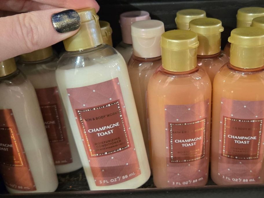 Bath & Body Works Mini Shampoo & Conditioners with a hand grabbing one from the shelf