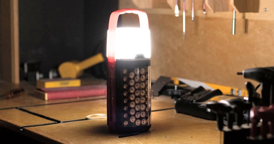 a lantern with a handle that also is a battery storage case on a work table in a garage