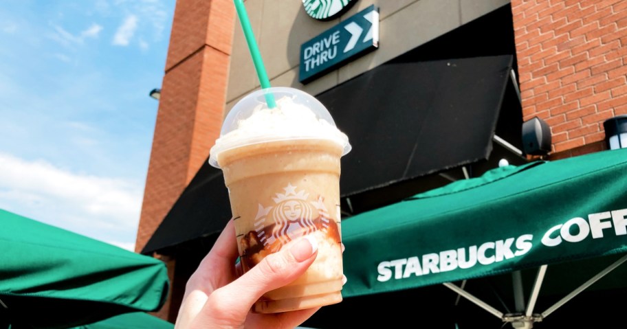 hand holding up a starbucks frappuccino outside starbucks store, one of our favorite food deals to share