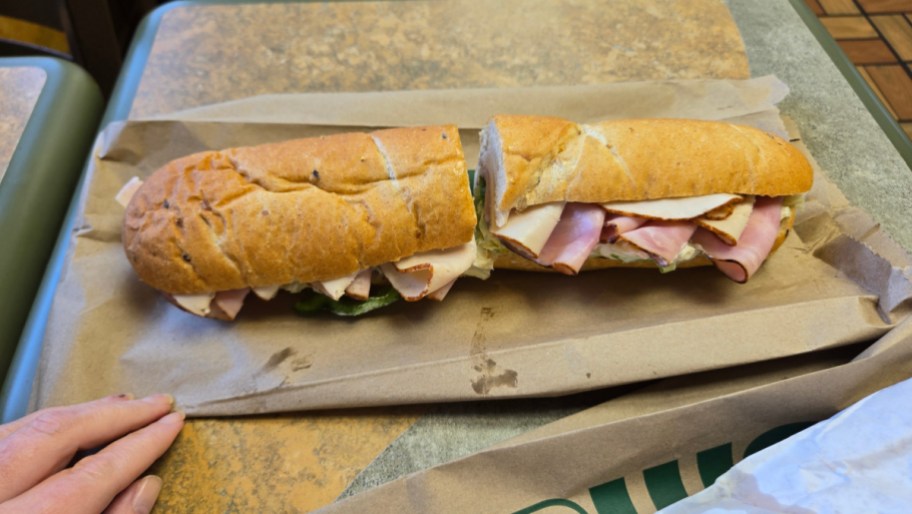 subway footlong sandwich with meat, cut in half and resting on a wrapper on a table