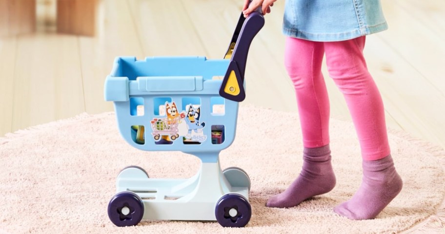 child pushing a small bluey shopping cart