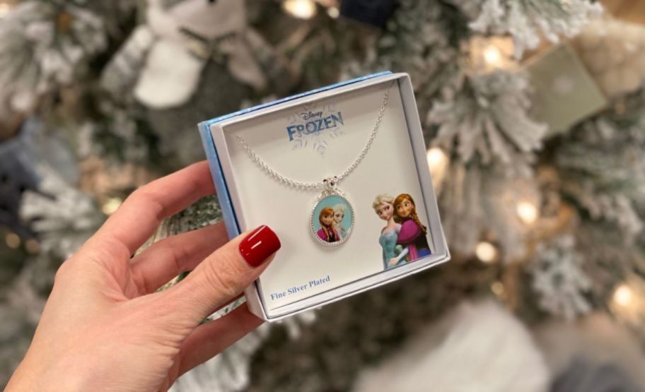 a womans hand holding a boxed pendant necklace