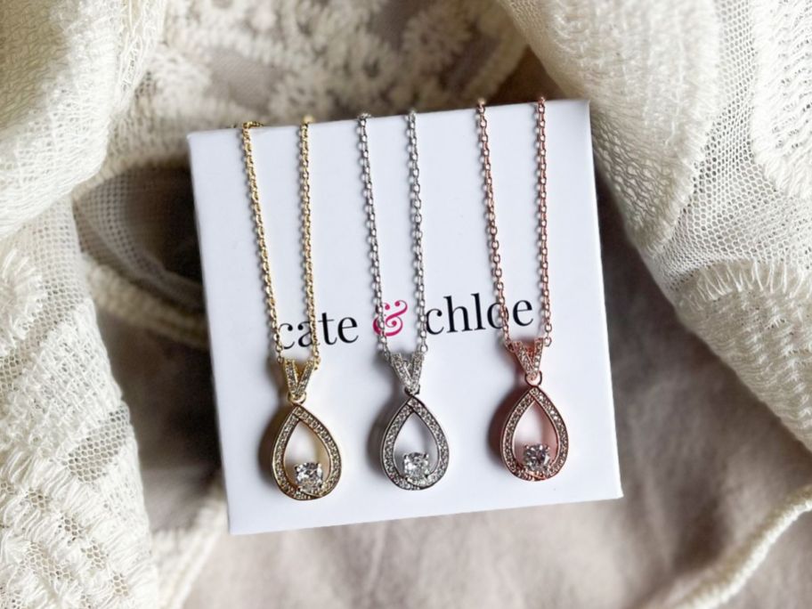 3 Cate & Chloe Arabella Necklaces in different colors resting on a Cate & Chloe gift box