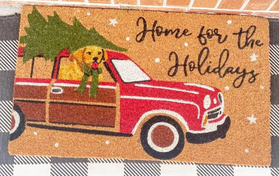 doormat printed with red station wagon with dog inside and tree on top and says "home for the holidays"