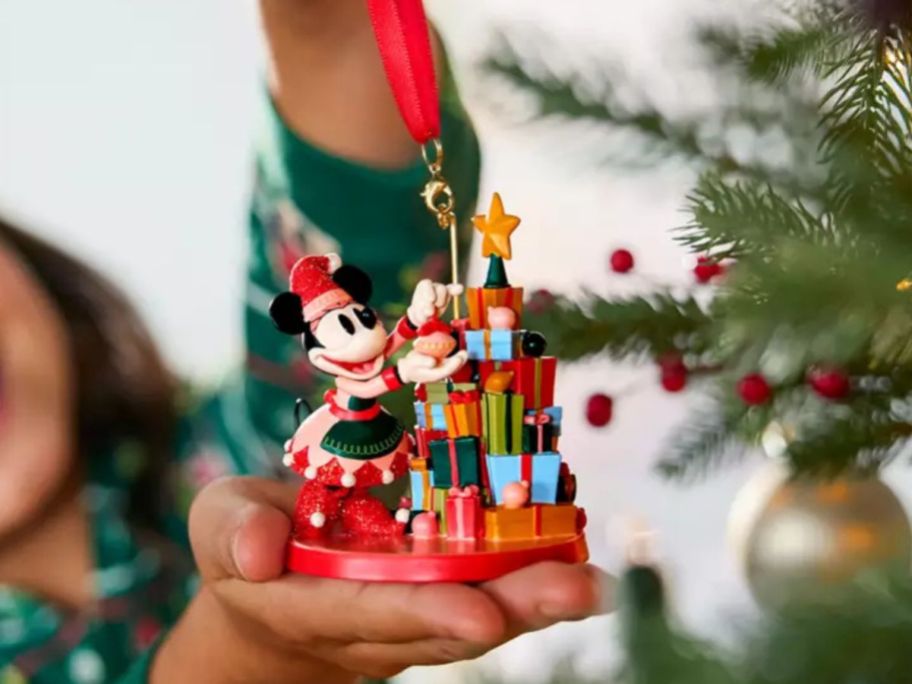 Girl putting a Disney Minnie Mouse christmas ornament on a tree