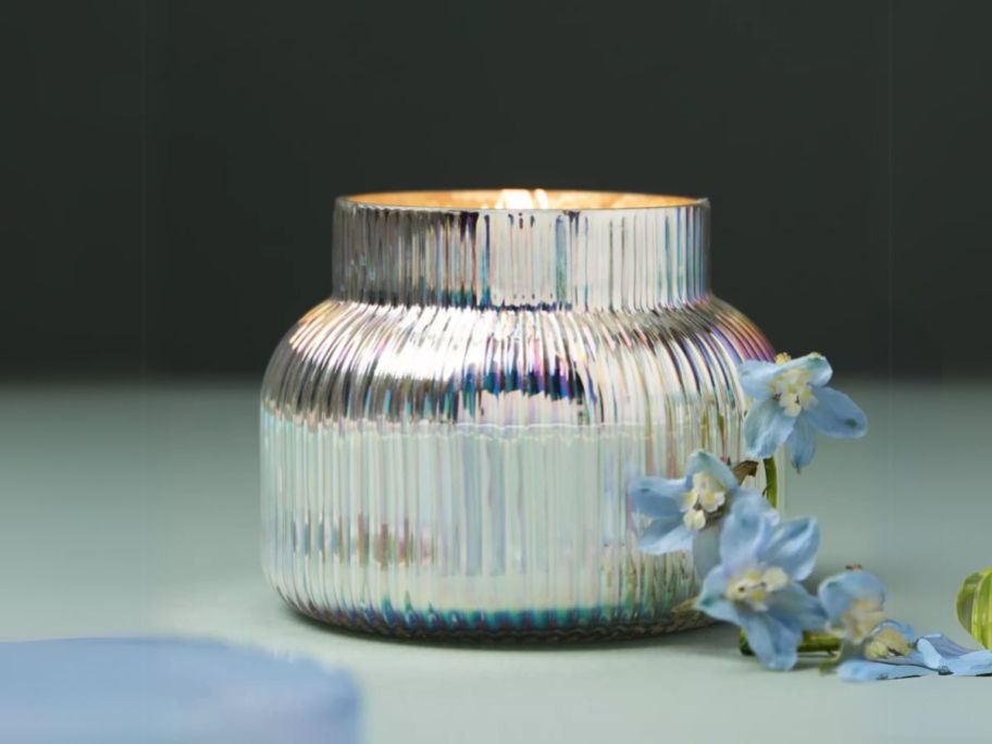 Anthropologie Capri Blue Volcano Ribbed Jar Candle on table with flowers next to it