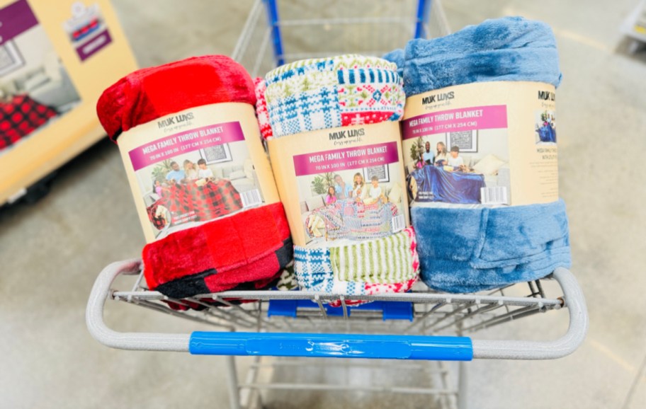 three muk luks family size blankets in their packaging in a walmart shopping cart