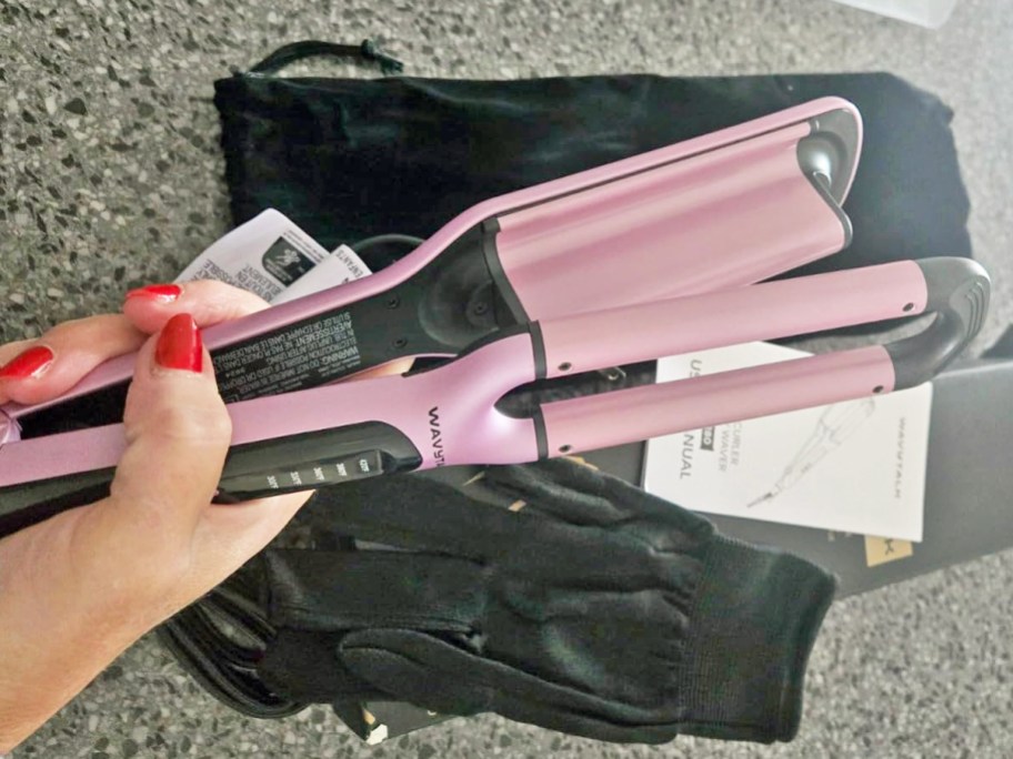 woman holding a pink and black beach waver tool