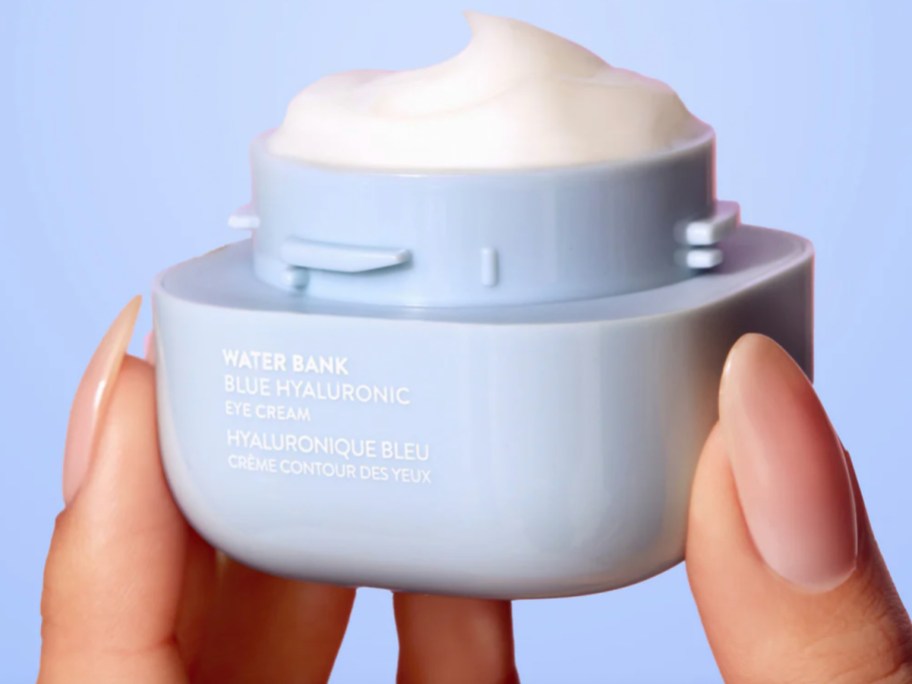 fingers holding opened eye cream