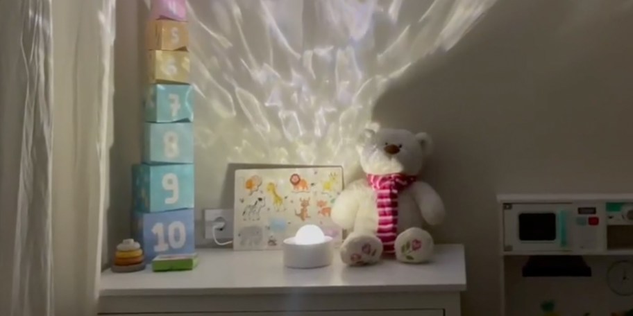 white projector on table with teddy bear and blocks