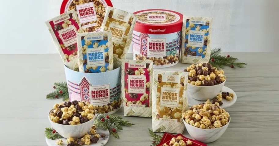 Harry & David Moose Munch Premium Popcorn Drums, one closed, one open showing the different flavor popcorn bags it comes with, some bags on in front and some popcorn is in bowls