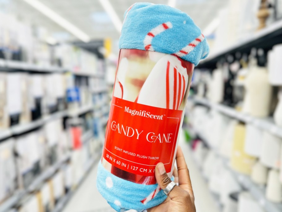 hand holding up a candy cane print throw blanket