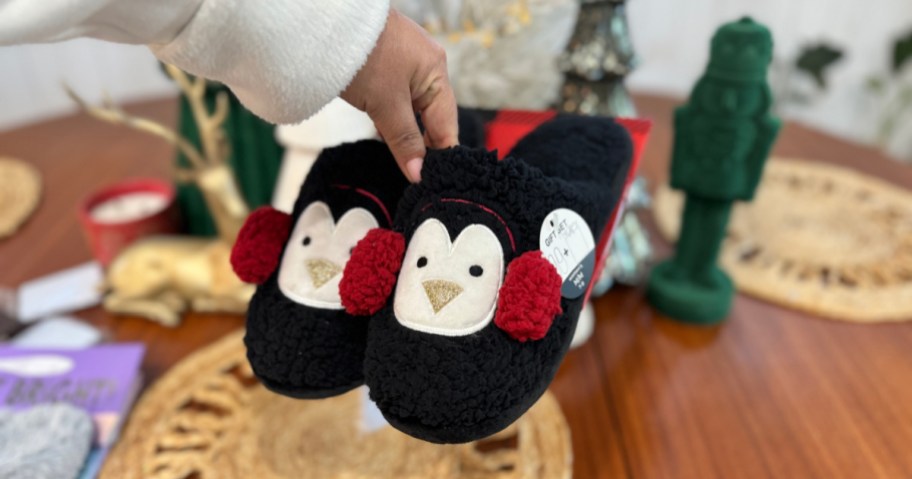 woman holding up pair of Dearfoams Penguin Slippers