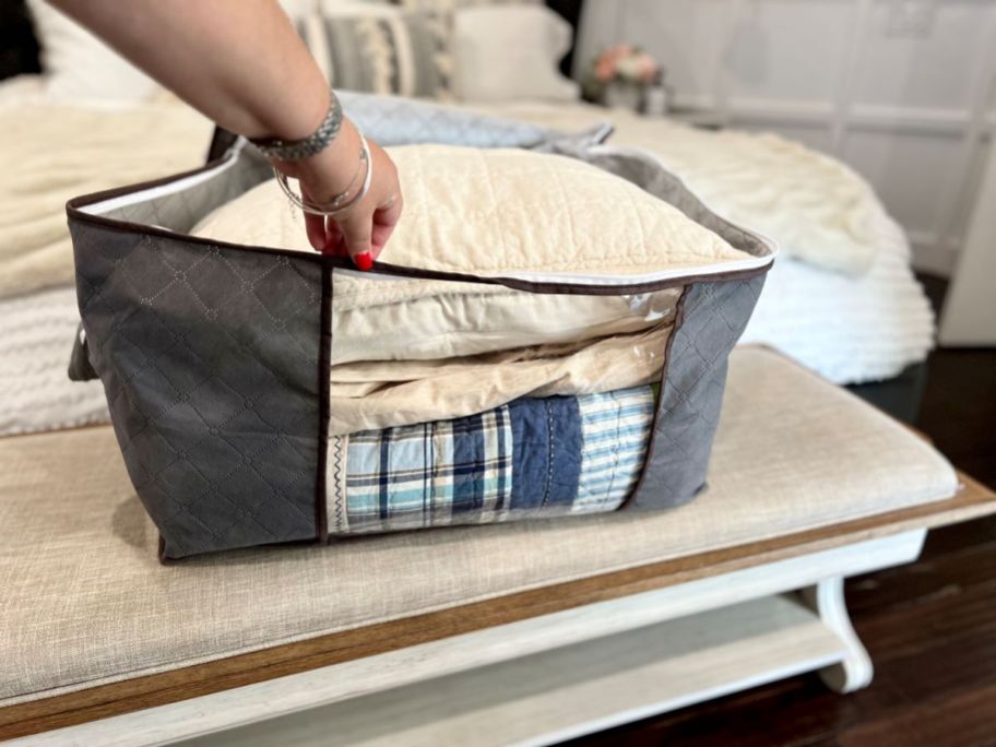 Hand grabbing a blanket out of a fabric storage bin