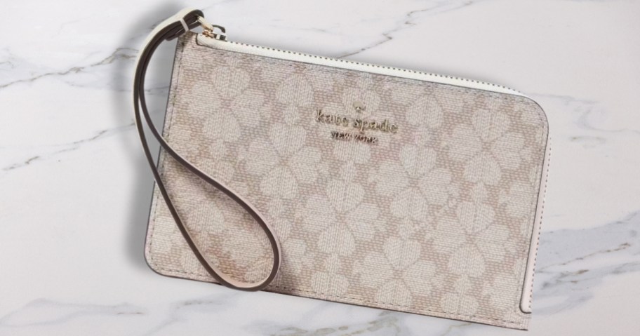 white and taupe kate spade wristlet with a floral medallion print on a marble counter