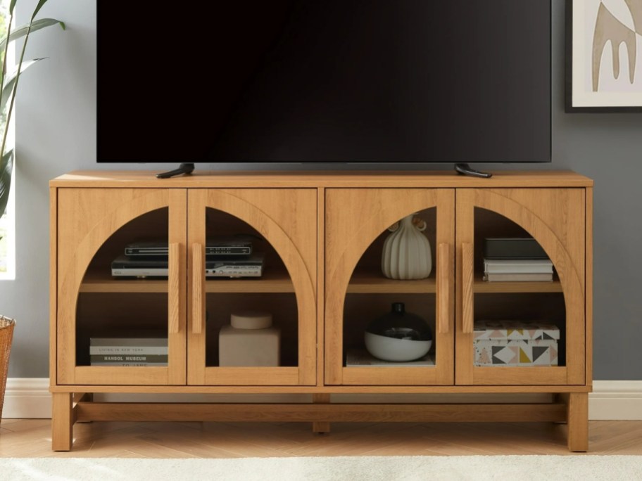 a light honey wood modern style tV stand with arched cut out glass doors