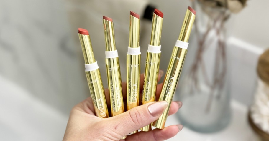 hand holding 5 gold Tarte Maracuja Juicy Lipsticks