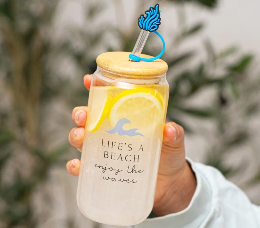 hand holding a glass tumbler with lemonade inside