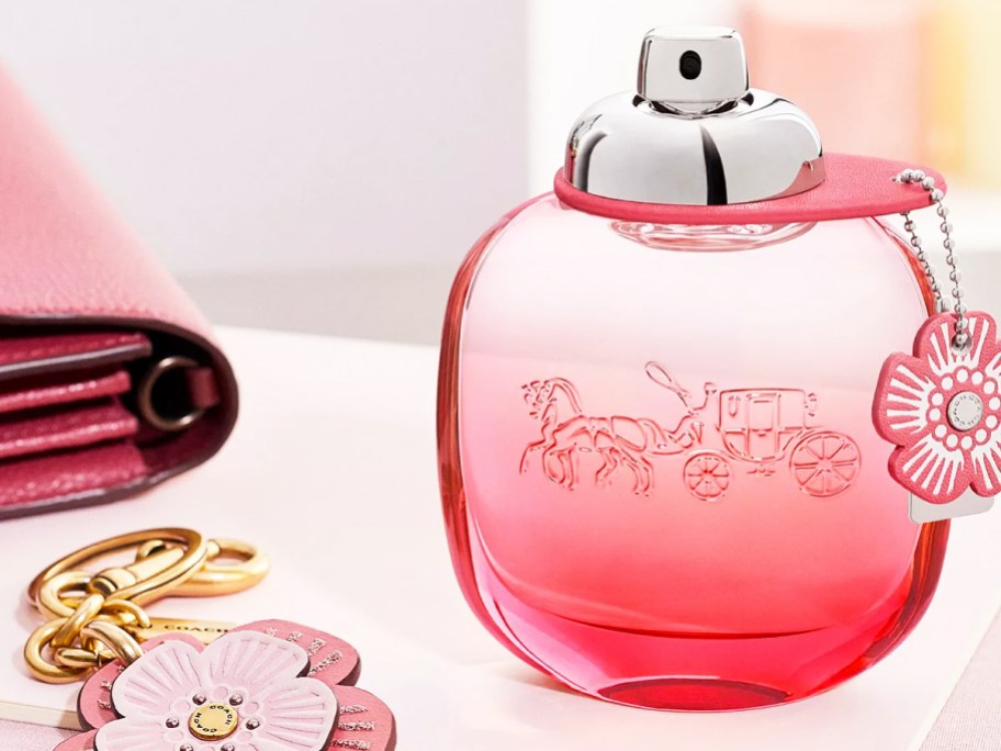 bottle of coach perfume with a flower charm near a flower keychain