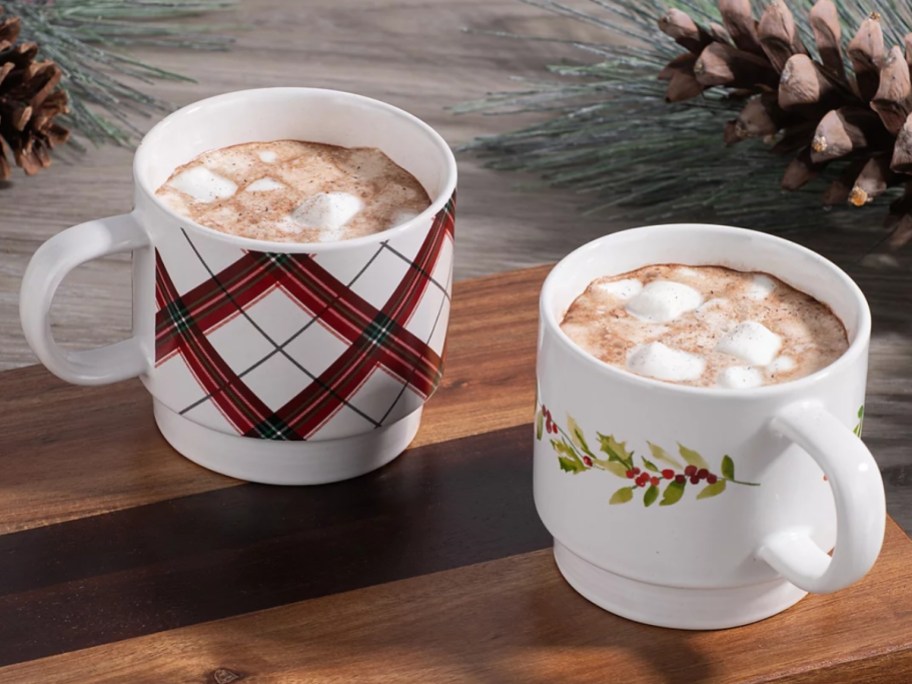 2 Christmas print coffee mugs with hot cocoa in them