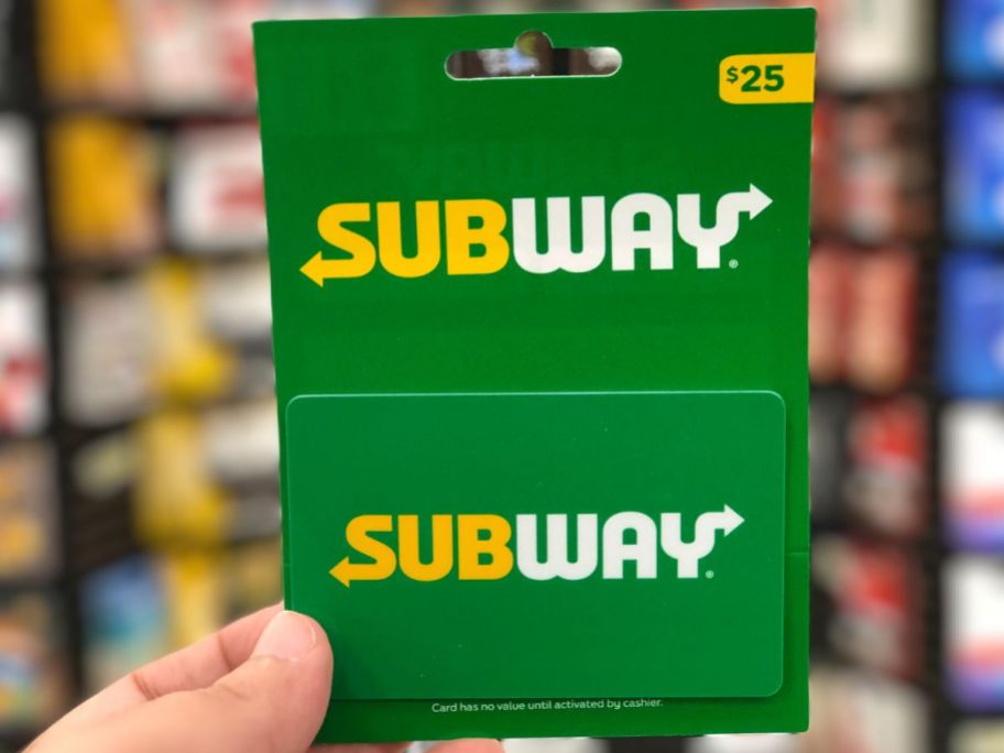 a mans hand holding a $25 subway gift card