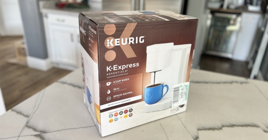 keurig k-expres coffee maker in <a href='https://sjf.a8c.myftpupload.com/product/sisters-in-style-collection' target='_blank' rel='follow'>box</a> on countertop” width=”912″ height=”479″></p>
<p>Race over to <a href=